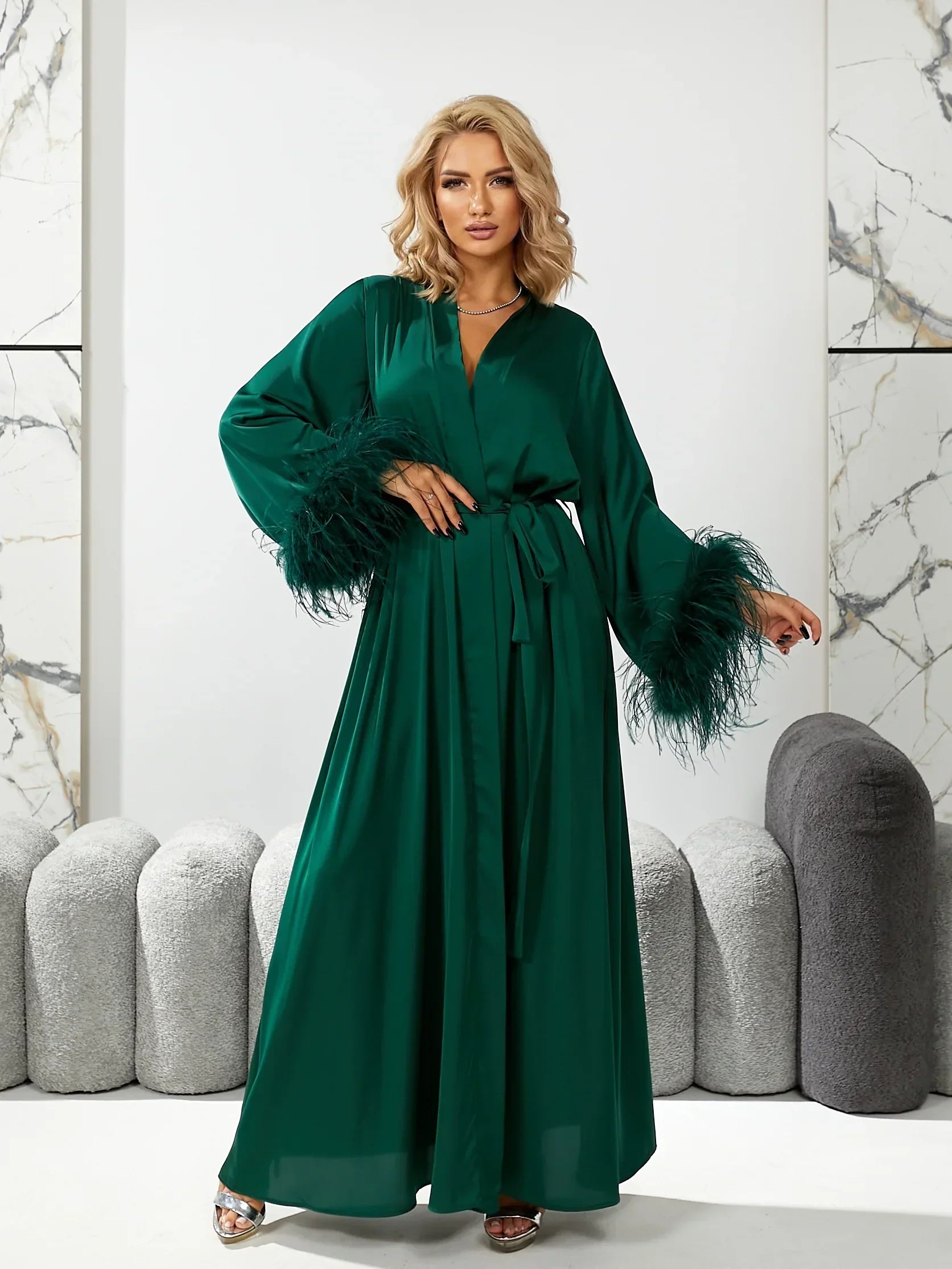 Woman wearing emerald green silk bridal robe with feather trim sleeves, perfect for wedding morning.