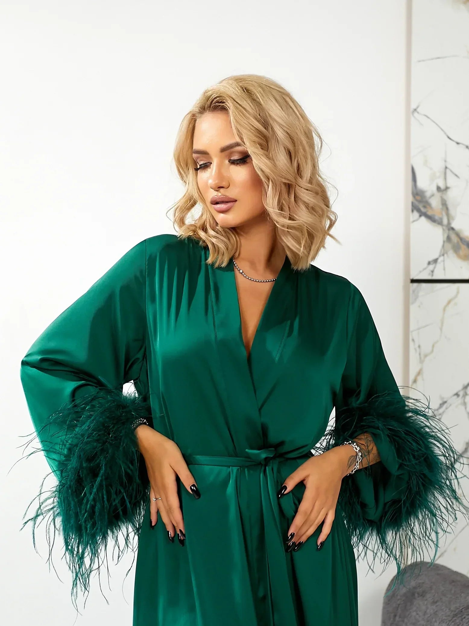 Woman in emerald green silk bridal robe with feather trim, perfect for wedding morning
