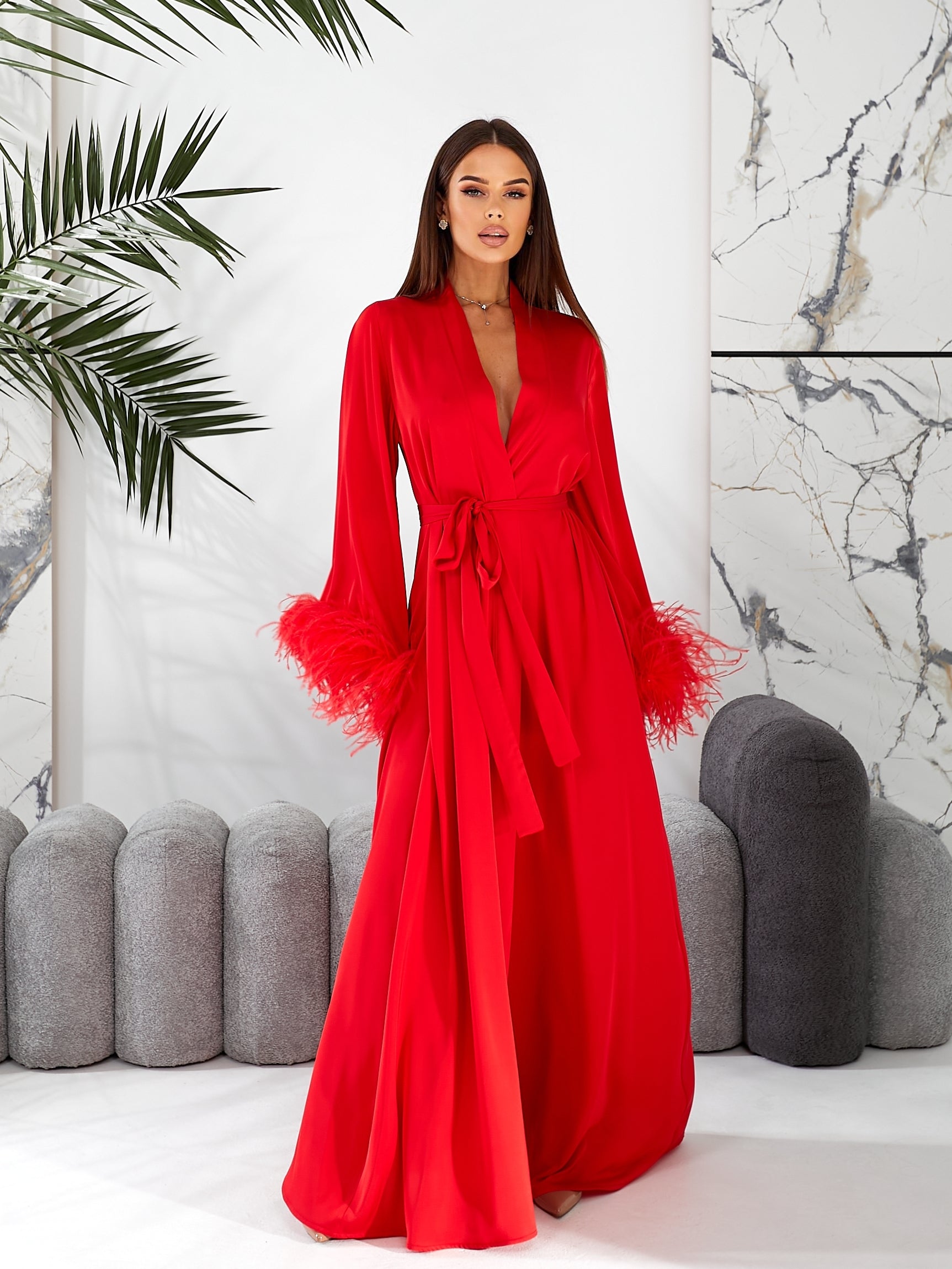 Feather robe silk robe longWoman wearing a red dress with feathered sleeves in an indoor setting.
