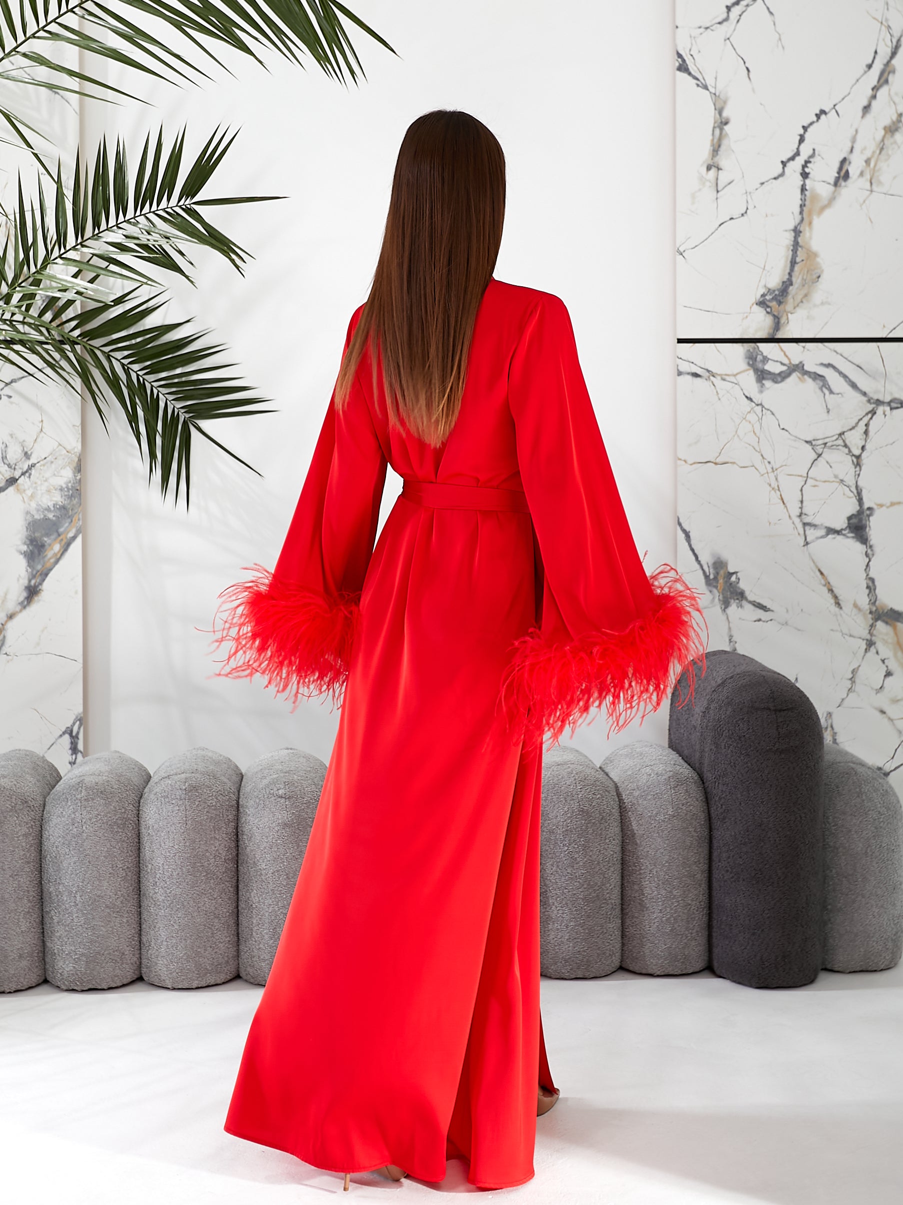 Long silk robe  Woman wearing a red dress with feathered sleeves in an indoor setting.