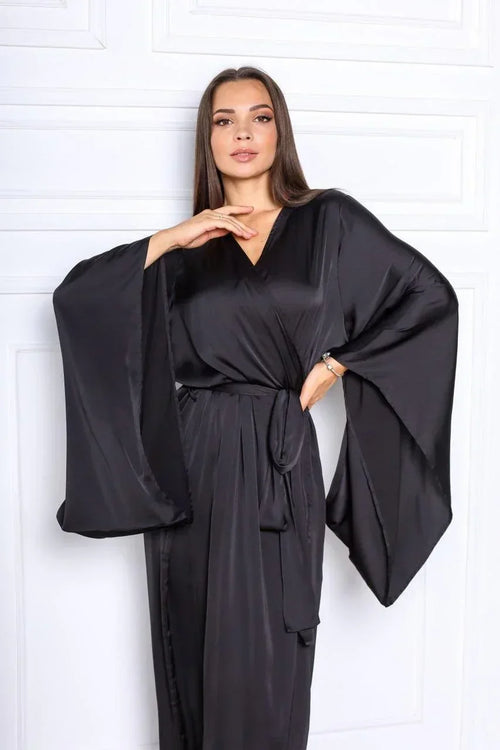 Woman wearing a black silk bridal robe with wide sleeves, perfect for wedding morning.